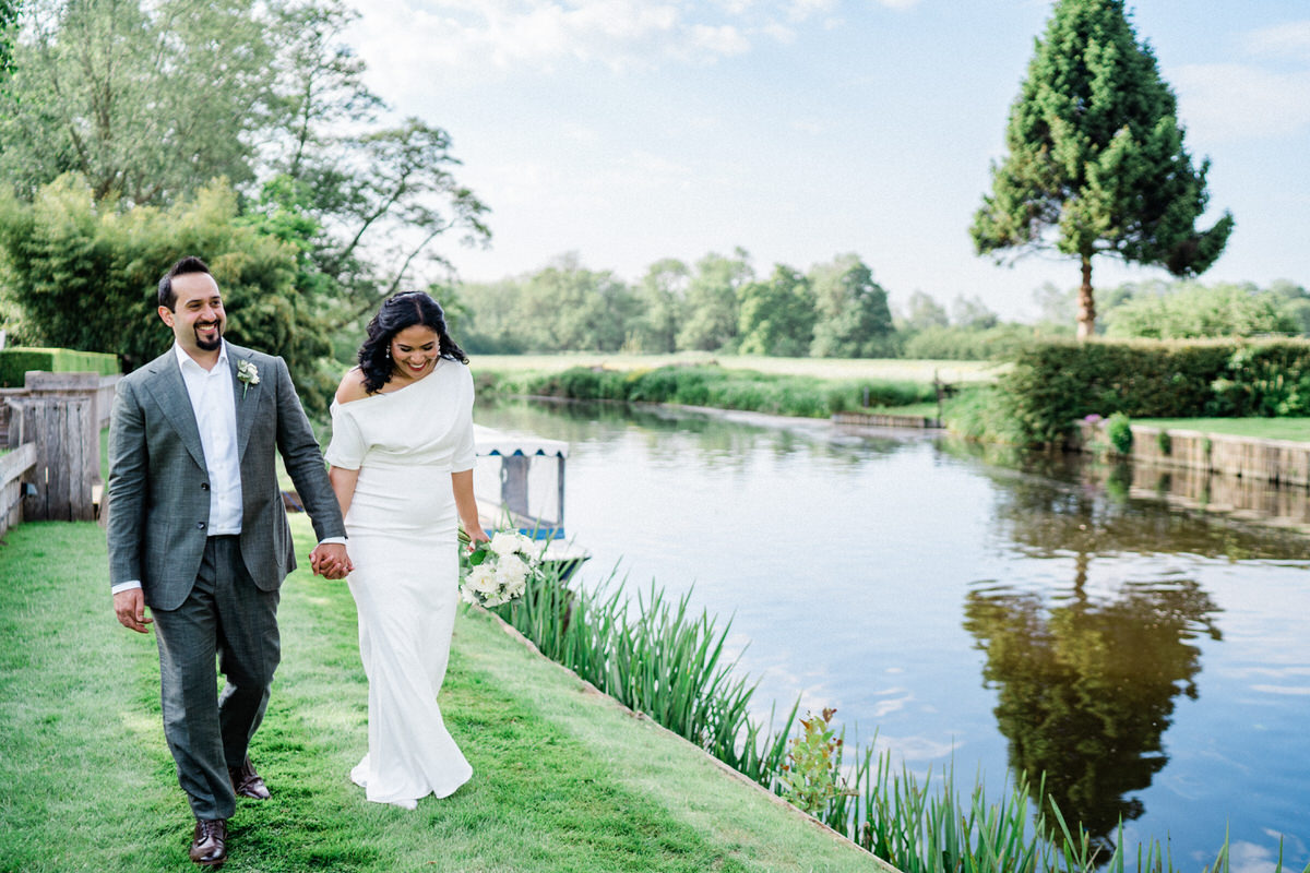 Wedding couple walking along the river Stour at Le Talbooth wedding venue.