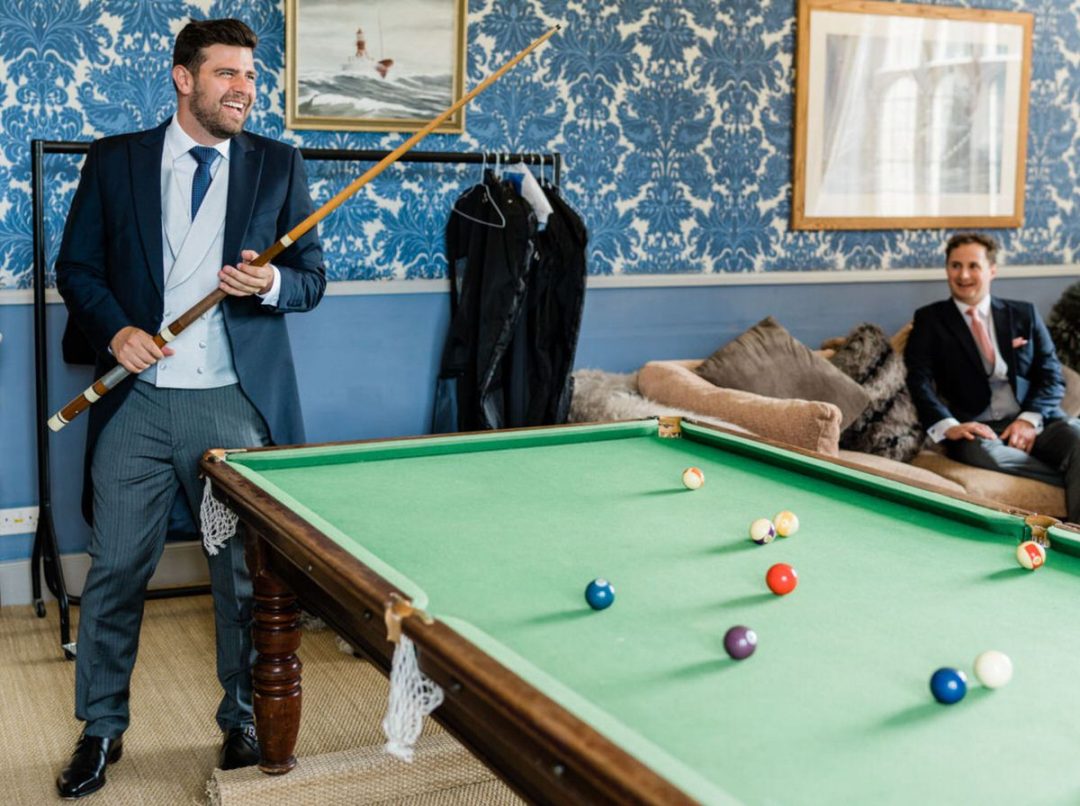 Groom playing snooker on wedding morning at Hengrave Hall.