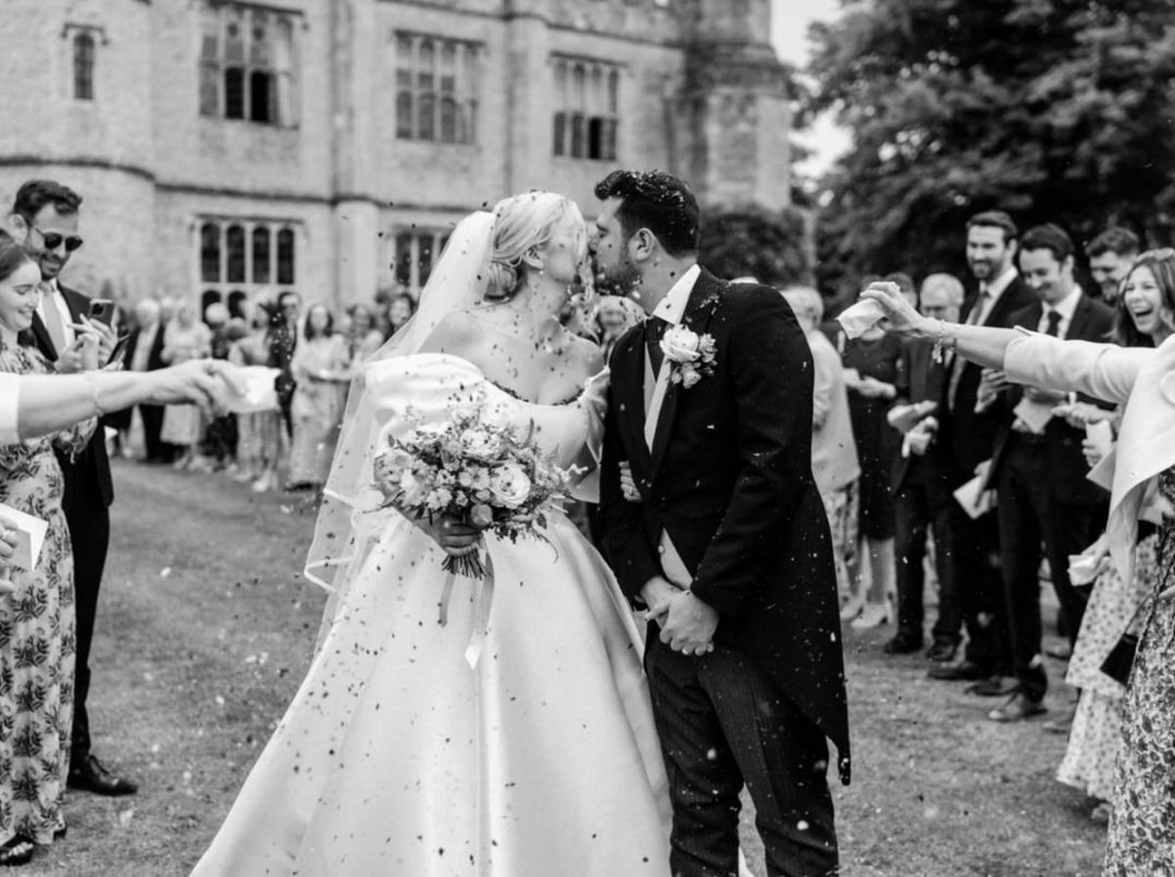 Wedding couple kiss after confetti at Hengrave Hall.