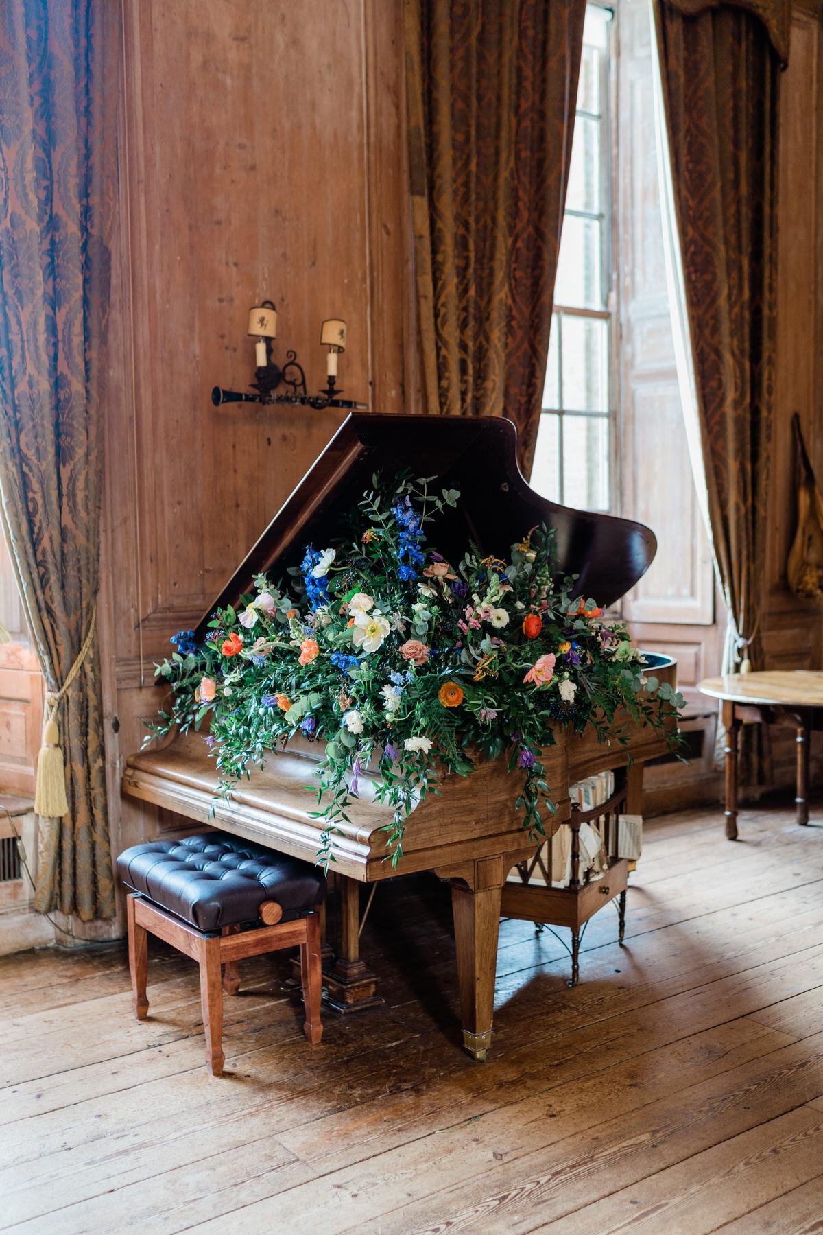 The grand piano at Glemham Hall wedding venue decorated with flowers.