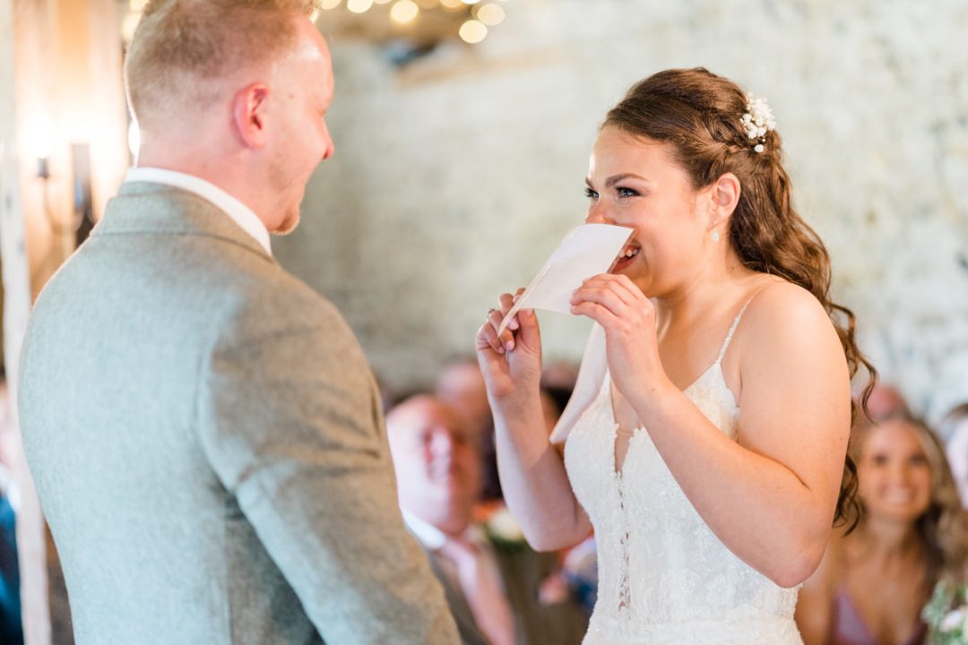 Giggly bride during ceremony in the Flint Barn at The Granary Estates